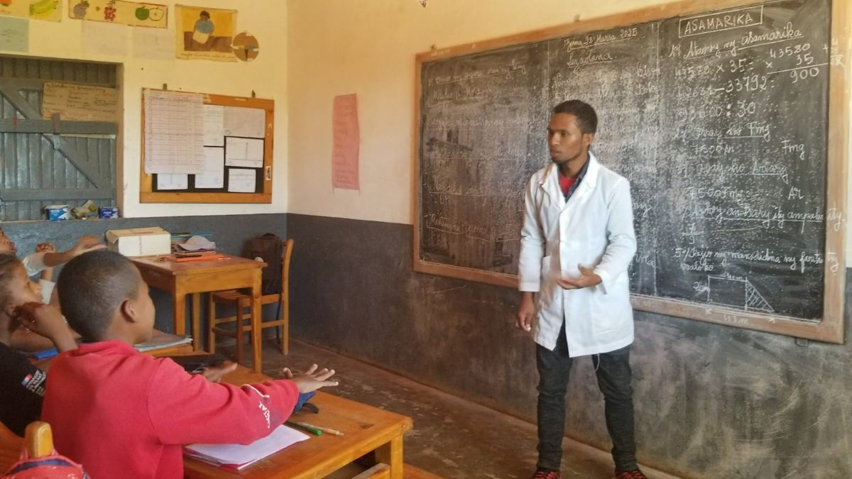 a teacher stands in front of a chalkboard, teaching a lesson