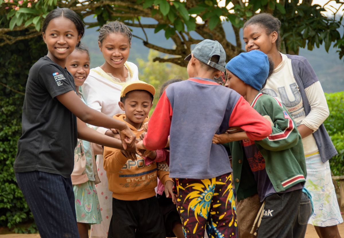 a group of boys and girls put their hands in the middle of their circle.