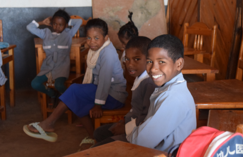 Jhonny smiles while posing for a photo in a classroom among other students