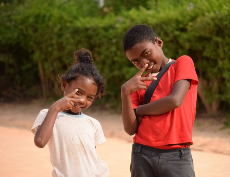 Two siblings, an older boy and a younger girl, smile and pose for the camera.