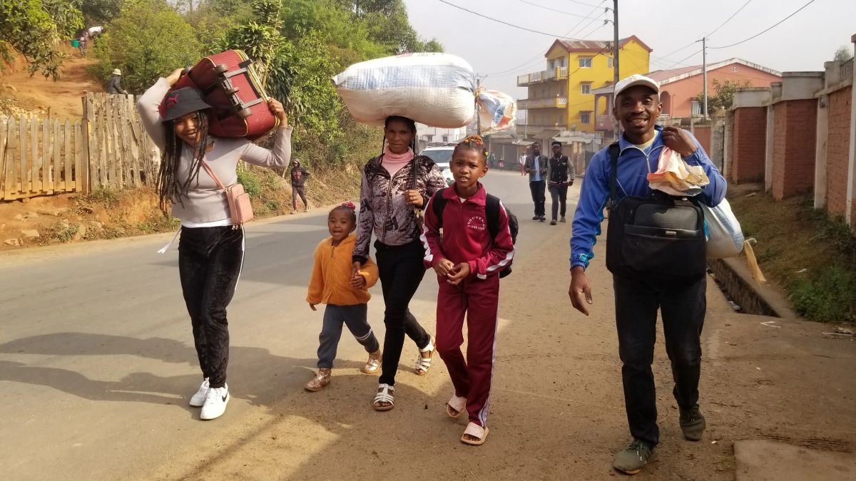 Aro and her family walk toward the bus station carrying their luggage