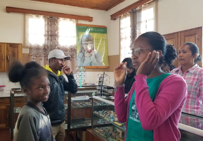 Two female students try on glasses at a nearby eye doctor