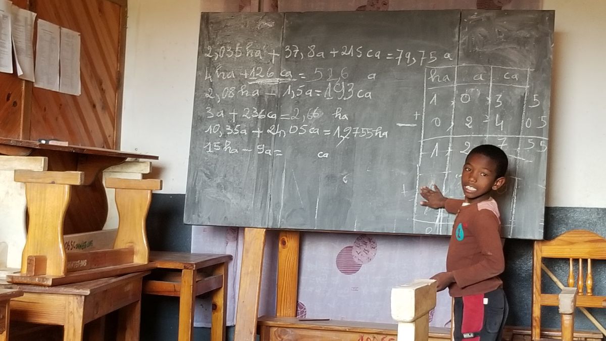 a young boy standing in front of a chalkboard